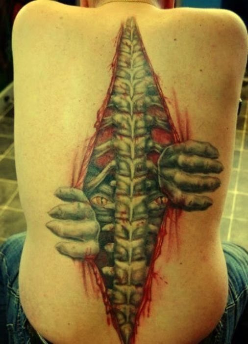 Tatuaje sobre la columna vertebral en el que se representan los huesos y de donde parece salir un extrao ser
