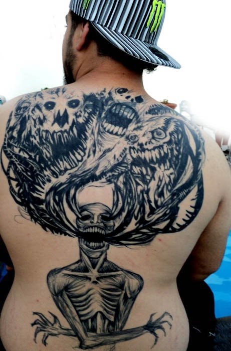 Espalda completamente tatuada con demonios y otros seres extraos
