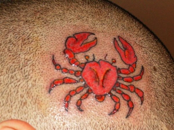 Tatuaje en la cabeza de un cangrejo de color rojo, tal vez pueda representar al signo zodiacal Cáncer, que como ya sabemos se representa con un cangrejo