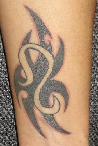Tatuaje de un tribal y un signo zodiacal, en concreto observamos que se ha realizado la silueta del signo zodiacal Leo