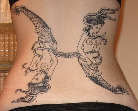 Tatuaje sobre la espalda de gran tamaño escenificando a dos sirenas en sentido opuestos, a las que se han dejado desnudos los pechos y que están unidas por una cuerda