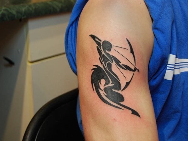 Tatuaje zodiacal en el brazo, del que no se han obtenido grandes resultados en su diseño, tal vez por conjugar los elementos tribales poco definidos con la silueta del hombre tirando una flecha con su arco