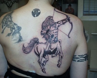 Tatuaje de un gran centauro sobre la espalda de esta chica, a este tattoo representativo de la mitología griega no se le ha dejado ni un detalle al azar, como podemos observar se le ha tatuado un largo pelo, un archo y una funda con las flechas, además podemos ver que esta chica tiene otros tatuajes por todo el cuerpo
