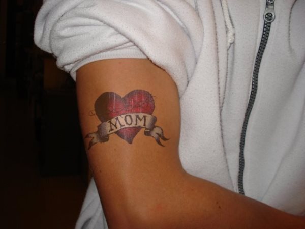 Tatuaje de un corazón con la palabra mamá en el brazo